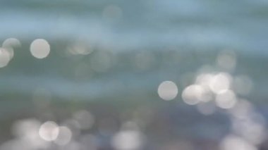 Güneşli bir yaz gününde deniz manzarası. Deniz Burnu. Mavi deniz suyu yüzeyli deniz manzarası, küçük dalgalanmalar ve güneşi yansıtan parlak lekeler. Bulanık soyut doğal arkaplan