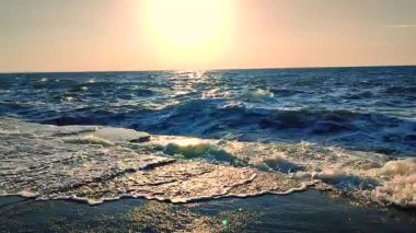 Yazın şafakta gün batımında denizde fırtına. Güneşli bir günde beton eski iskeleye beyaz köpüklü büyük deniz dalgaları çarpıyor. Çimento iskelesine ve temiz mavi gökyüzüne çarpan büyük dalgalardan bir sürü sıçrama.