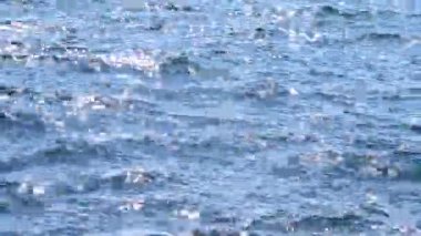 Deniz. Mavi denizin soyut görüntüsü, suda dalgalanmalar ve güneşli bir yaz gününde parlayan beyaz güneş. Doğa. Doğal arka plan. Yaz tatili turizmi kavramını