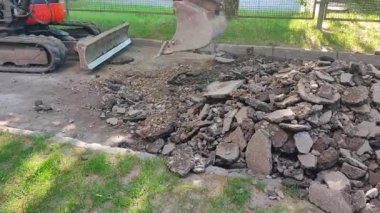 Kovası yolda asfaltı kıran bir traktör. Traktör, asfalt yolu kovayla parçalıyor.