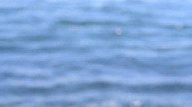 Güneşli bir yaz gününde deniz manzarası. Deniz Burnu. Mavi deniz suyu yüzeyli deniz manzarası, küçük dalgalanmalar ve güneşi yansıtan parlak lekeler. Bulanık soyut doğal arkaplan