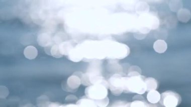 Deniz. Mavi denizin soyut görüntüsü, suda dalgalanmalar ve güneşli bir yaz gününde parlayan beyaz güneş. Doğa. Doğal arka plan. Arka plan bulanık. Yaz tatili turizmi kavramını