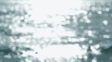 Deniz. Mavi denizin soyut görüntüsü, suda dalgalanmalar ve güneşli bir yaz gününde parlayan beyaz güneş. Doğa. Doğal arka plan. Arka plan bulanık. Yaz tatili turizmi kavramını