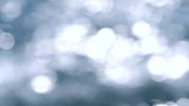 Güneşli bir yaz gününde soyut deniz manzarası. Bulanık doğa geçmişi. Birçok beyaz, yuvarlak, deniz dalgalarının mavi yüzeyinde parlayan güneşi yansıtan noktalar var. Doğa.