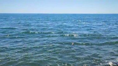 Deniz manzaralı. Güneşli sıcak yaz gününde mavi deniz manzarası. Dalgalanmalı ve beyaz güneş yansımalı deniz suyu yüzeyinin soyut görüntüsü. Hiç kimse. Deniz Burnu. Deniz manzarası. Doğa. Doğal arkaplan