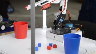 Robot otomatik el küpleri alıyor ve cam takıyor. Otomatik robotik kol, küpün rengini ayırt eder ve aynı renkte cam koyar. Otomasyon, modern teknolojiler. Yapay Zeka