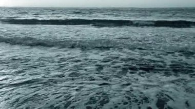 Deniz dalgaları yazın gün batımında deniz kıyısında kumlu bir sahilde dalgalanır. Doğa. Doğal arka plan. Mavi renk