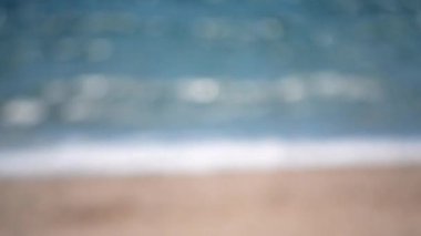 Deniz sahili kum dalgaları güneşli yaz günlerinde dalgalanır. Güneşli bir günde deniz ve kumsalın su yüzeyinin soyut görüntüsü deniz yüzeyinde güneşten gelen bulanık beyaz bokeh. Bulanık arkaplan