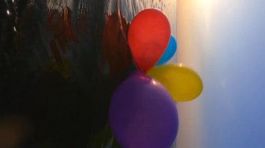 Gün batımında ve şafakta deniz suyunun yüzeyinde yüzen kurdeleyle bağlanmış bir sürü renkli balon. Gün batımında ve şafakta ufkun üzerinde parlayan güneş. Yavaş çekim