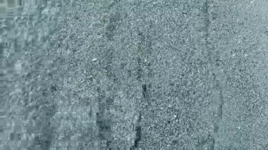 Kumsalda kumsalda yuvarlanan küçük deniz dalgalarının temiz şeffaf sularının soyut görüntüsü. Deniz dalgalarının gölgeleri ve kumlu zeminde su yüzeyinden parlayan güneş. Doğal arkaplan Mavi