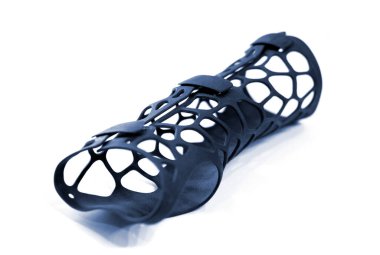 Beyaz arka planda izole edilmiş erimiş siyah plastik baruttan alınan 3D yazıcıya basılmış korse protezi. 3D yazıcıda tıbbi ortopedik fiksör kaplaması oluşturuldu. 3D yazıcı teknolojileri