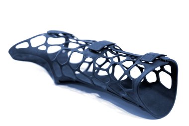 Beyaz arka planda izole edilmiş erimiş siyah plastik baruttan alınan 3D yazıcıya basılmış korse protezi. 3D yazıcıda tıbbi ortopedik fiksör kaplaması oluşturuldu. 3D yazıcı teknolojileri