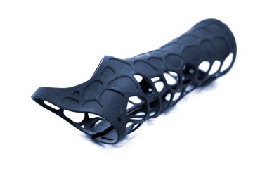 Beyaz arka planda izole edilmiş erimiş siyah plastik baruttan alınan 3D yazıcıya basılmış korse protezi. 3D yazıcıda tıbbi ortopedik fiksör kaplaması oluşturuldu. 3D yazıcı teknolojileri