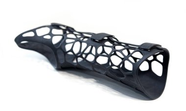 Beyaz arka planda izole edilmiş erimiş siyah plastik baruttan alınan 3D yazıcıya basılmış korse protezi. 3D yazıcıda tıbbi ortopedik fiksör kaplaması oluşturuldu. 3D yazıcı teknolojileri