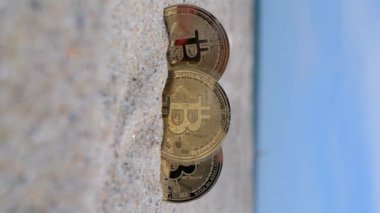 Üç Bitcoin BTC madeni parası. Bitcoin BTC sikkenin yarısı kumlu sahilde kumlara gömülü güneşli bir yaz gününde mavi deniz kıyısında gökyüzü. Şifreleme Ağı 3 kripto para birimlerini şifreli düşey göster