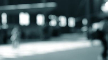 Arka plan bulanık. Birçok insan gün boyunca pencereli büyük bir odanın içinde yürür. Siyah siluetler, insanlar. Mavi beyaz siyah renk