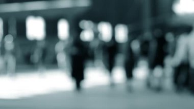 Arka plan bulanık. Birçok insan gün boyunca pencereli büyük bir odanın içinde yürür. Siyah siluetler, insanlar. Mavi beyaz siyah renk