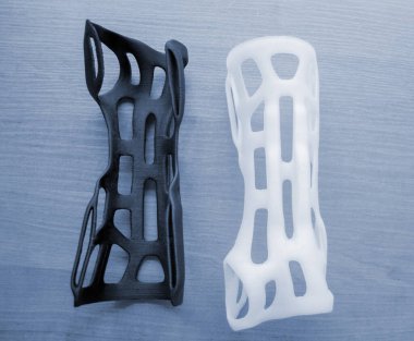 Elle sabitlenmiş korse protez landalı erimiş plastikten üç boyutlu bir yazıcıya basılmış. Tıbbi ortoz, fiksatör, 3D yazıcıda oluşturulan plastik kaplama. Yeni modern tıbbi 3D baskı teknolojileri