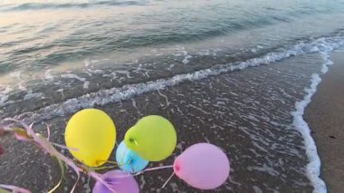 Deniz kıyısında renkli balonlarla oynayan bir adam var. Gün batımında deniz sahilinde bir sürü renkli balon elinde. Çok renkli balonlar kurdeleyle bağlanmış. Yavaş çekim