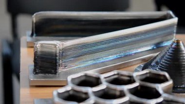 Masanın üzerindeki erimiş metal lifinden üç boyutlu yazıcı ile basılmış nesneler.