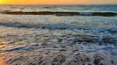 Güneşli bir sabahta kumsalın kumlu sahilinde beyaz köpükle dalgalar süzülüyor. Doğa. Doğal arkaplan