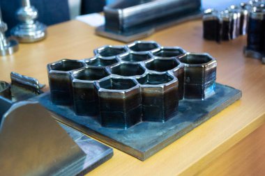 Masanın üzerindeki erimiş metal lifinden üç boyutlu yazıcı ile basılmış nesneler.