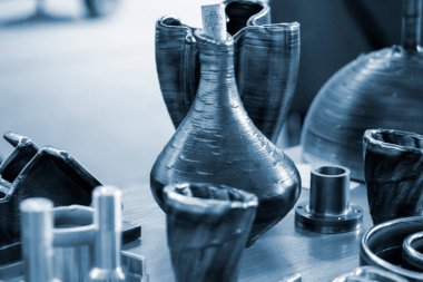 Masanın üzerindeki erimiş metal lifinden üç boyutlu yazıcı ile basılmış nesneler.