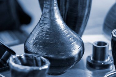 Masanın üzerindeki erimiş metal lifinden üç boyutlu yazıcı ile basılmış nesneler.