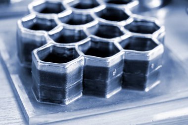 Masanın üzerindeki erimiş metal lifinden üç boyutlu yazıcı ile basılmış nesneler.