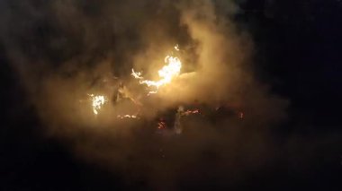 Saman ve gece dumanından oluşan sönen ateşin alevleri. Kamp ateşi ve kuru saman. Yangında saman yakmak ve siyah arka planda bir sürü duman çıkarmak. Duman ve ateş. Doğal arkaplan