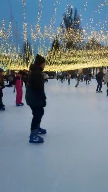 Kyiv, Ukrayna, 2 Mart 2025 'te birçok insan beyaz halk buz pateni pistinde paten kayıyor. İnsanlar kış günü buz pateni pistinde kayıyorlar. Buz pateni pistindeki insanların dinlenmesi. Halka açık buz pateni pisti. Buz pateni. Dikey