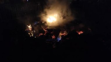 Saman ve gece dumanından oluşan sönen ateşin alevleri. Kamp ateşi ve kuru saman. Yangında saman yakmak ve siyah arka planda bir sürü duman çıkarmak. Duman ve ateş. Doğal arkaplan