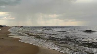 Yağmur fırtınası ve kumlu sahil kıyıları. Kara fırtına bulutları, yağmur, deniz yüzeyi ve kumlu sahil. Doğa. Doğal arka plan. Fırtınalı hava. Denizde fırtına.