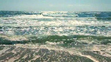 Beyaz köpüklü temiz deniz dalgaları ve güneşli bir yaz gününde mavi gökyüzü ile kumlu sahil sahilinde süzülen güneş ışığı. Deniz kıyısında. Kumsal. Doğa arkaplanı. Doğal arkaplan