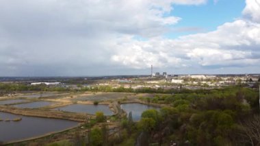 Bulutlu bahar gününde balık çiftçiliği ve endüstriyel binalar için yapay göllerin görüntüsü. Ağaçlar, su göletleri göletteki büyük bulutlar. Panoramik manzara. Hava aracı görünümü