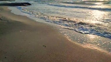 Beyaz köpüklü deniz dalgaları kumlu sahil sahilinde yuvarlanıyor. Deniz kıyısındaki sarı kumdaki açık mavi deniz dalgalarının görüntüsü. Deniz Burnu. Deniz manzarası. Kıyı manzarası. Doğa. Doğal arkaplan.