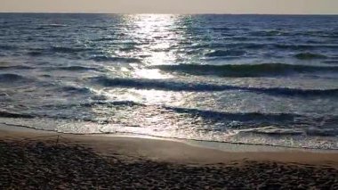 Beyaz köpüklü deniz dalgaları kumlu sahil sahilinde yuvarlanıyor. Deniz kıyısındaki sarı kumdaki açık mavi deniz dalgalarının görüntüsü. Deniz Burnu. Deniz manzarası. Kıyı manzarası. Doğa. Doğal arkaplan.