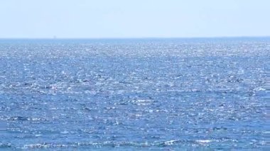 Deniz Burnu. Güneşli bir günde deniz manzarası. Mavi denizin yüzeyinde beyaz güneş parlıyor ve mavi gökyüzü. Dalgalı ve beyaz benekli mavi deniz manzarası. Çevre. Doğa. Doğal arka plan. Kimse.