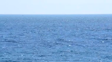 Deniz Burnu. Güneşli bir günde deniz manzarası. Mavi denizin yüzeyinde beyaz güneş parlıyor ve mavi gökyüzü. Dalgalı ve beyaz benekli mavi deniz manzarası. Çevre. Doğa. Doğal arka plan. Kimse.