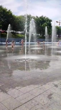 Odessa Ukrayna, 2 Temmuz 2023: Güneşli yaz günlerinde, yaya çeşmesinden su fışkırtan çocuklar. Büyük halka açık sokak fıskiyeleri ve şehir meydanındaki çocuklara su sıçratma. Dikey