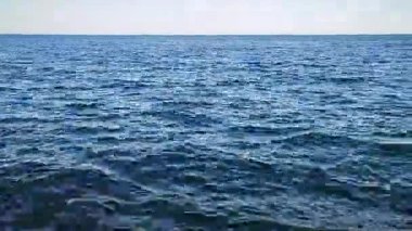 Deniz manzaralı. Sakin ve rüzgarsız havada, mavi deniz ve mavi gökyüzünün panoramik görüntüsü. Suyun yüzeyinde dalgalanmalar. Deniz Burnu. Deniz manzarası. Skyline. Hiç kimse. Doğa arkaplanı. Doğal arkaplan.