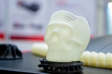 Yüzeyde erimiş beyaz plastikten çıkan 3 boyutlu insan kafatası prototipi. Üç boyutlu model. Katkı sağlayan ilerici tıbbi teknoloji. Modern yeni baskı üretim endüstrisi