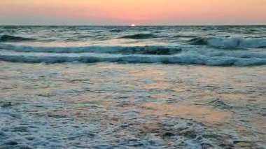 Gün batımında ve şafakta denizde beyaz köpüklü büyük dalgalar. Fırtına. Mavi deniz, kızıl gökyüzü. Fırtınalı deniz. Kıyı sahili kıyısı. Deniz kıyısı kıyısı. Doğal arka plan doğa fırtınası