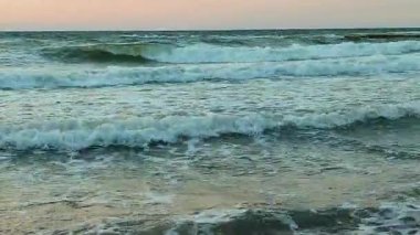 Gün batımında ve şafakta denizde beyaz köpüklü büyük dalgalar. Fırtına. Mavi deniz, kızıl gökyüzü. Fırtınalı deniz. Kıyı sahili kıyısı. Deniz kıyısı kıyısı. Doğal arka plan doğa fırtınası