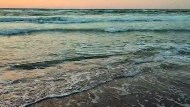 Gün batımında ve şafakta denizde beyaz köpüklü büyük dalgalar. Fırtına. Mavi deniz, kızıl gökyüzü. Fırtınalı deniz. Kıyı sahili kıyısı. Deniz kıyısı kıyısı. Doğal arka plan doğa fırtınası