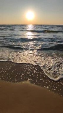 Denizde şafak vakti. Denizde gün batımı. Gündoğumu, okyanusta gün batımı. Parlayan güneş, mavi dalgalar, kumsal. Deniz manzarası manzarası. Güneş ışığı. Deniz kıyısında. Doğal arka plan, doğa. Dikey