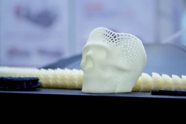 Yüzeyde erimiş beyaz plastikten küçük bir insan kafatası 3D prototipi var. Üç boyutlu model. Modern yeni baskı üretim endüstrisi. Katkı sağlayan ilerici tıbbi teknoloji.