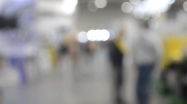 Binada yürüyen insanlar. Duvarları, zemini, tavan lambaları olan bir bina. İçerideki insanların siluetleri. Bir sürü insan yürüyor. Erkekler ve kadınlar uzun salonda. Sergi merkezi. Bulanık arkaplan