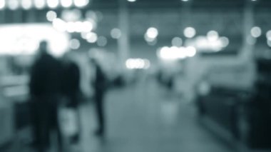 Binada yürüyen insanlar. Duvarları, zemini, tavan lambaları olan bir bina. İçerideki insanların siluetleri. Bir sürü insan yürüyor. Erkekler ve kadınlar uzun salonda. Sergi merkezi. Bulanık arkaplan