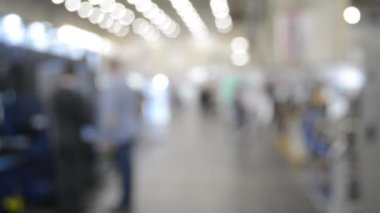 Binada yürüyen insanlar. Duvarları, zemini, tavan lambaları olan bir bina. İçerideki insanların siluetleri. Bir sürü insan yürüyor. Erkekler ve kadınlar uzun salonda. Sergi merkezi. Bulanık arkaplan